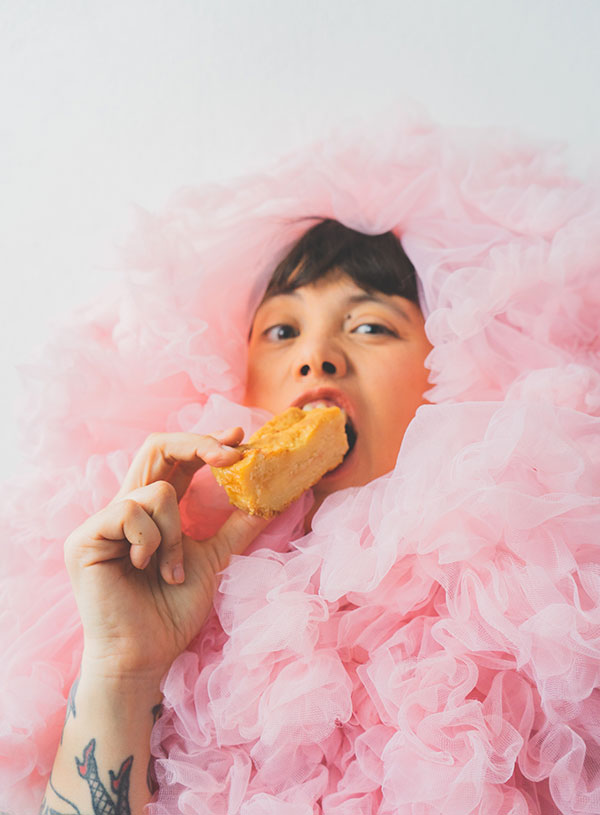Dorothy Porker surrounded by pink tule ruffles biting into a butterbar