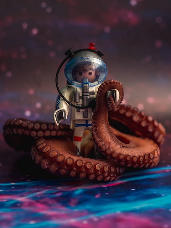 A Playmobil astronaut, surrounded by purple cooked octopus tentacles on a space backdrop