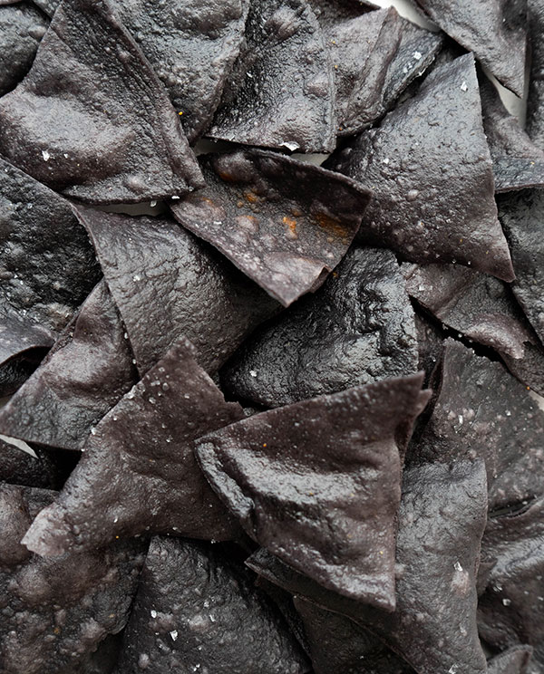 A closeup of salted black totopos (fresh fried nachos made from fresh tortillas).