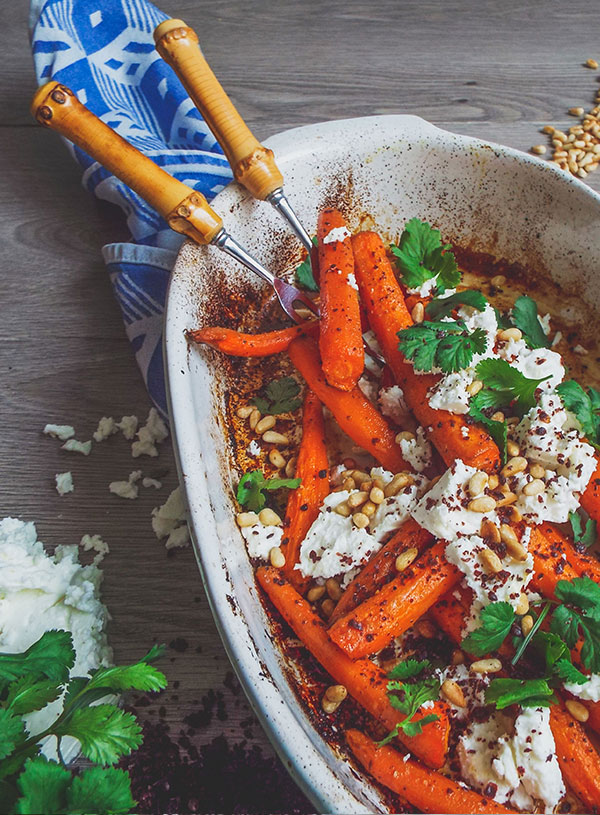 An oven dish filled with roast carrots, feta, pine nuts and coriander